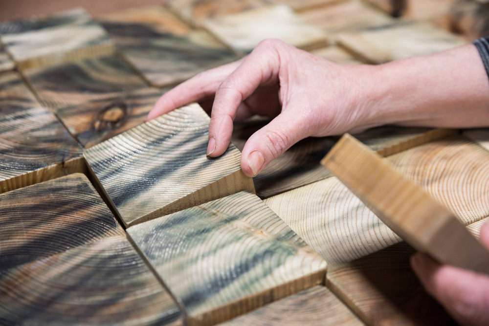 Selecteren en ordenen van houten elementen tijdens het maakproces van een 3D houten wandkunstwerk op maat